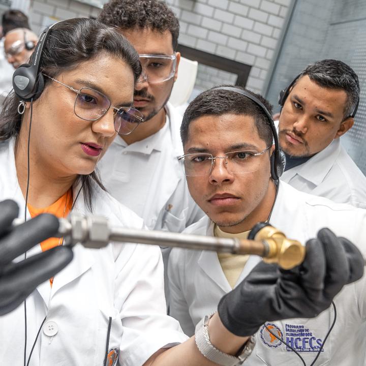 Four people look at a technical device during a training session.