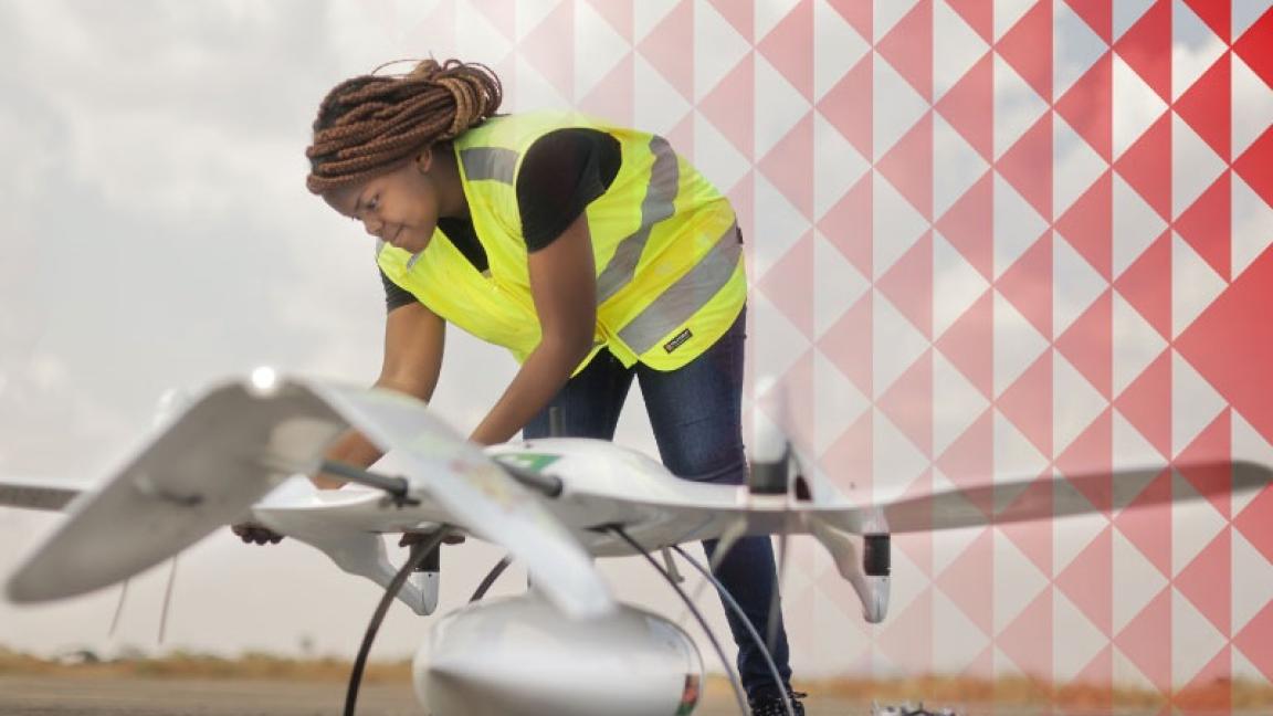A woman in a security vest is working on a drone.