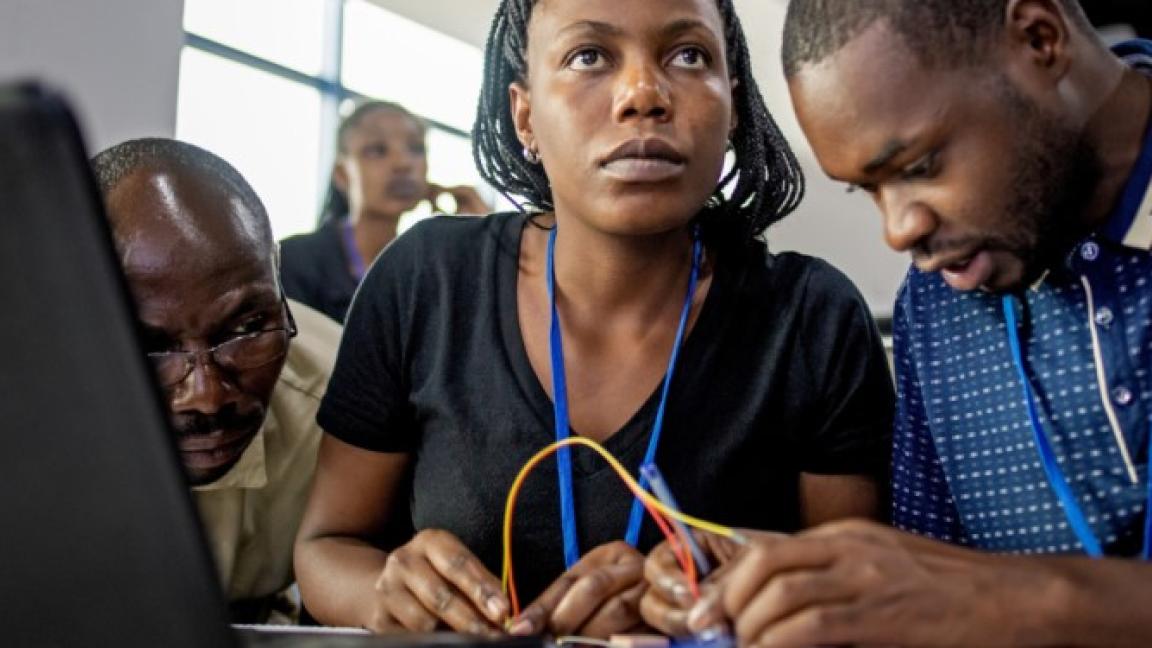 Drei IT-Entwickler*innen basteln an einem Computer.