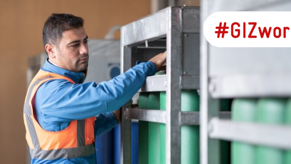 A man works with hydrogen cylinders that are stored in a steel container.