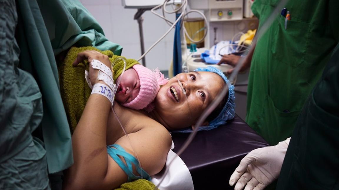 Eine Person, die mit einem Baby in einem Krankenhausbett liegt.