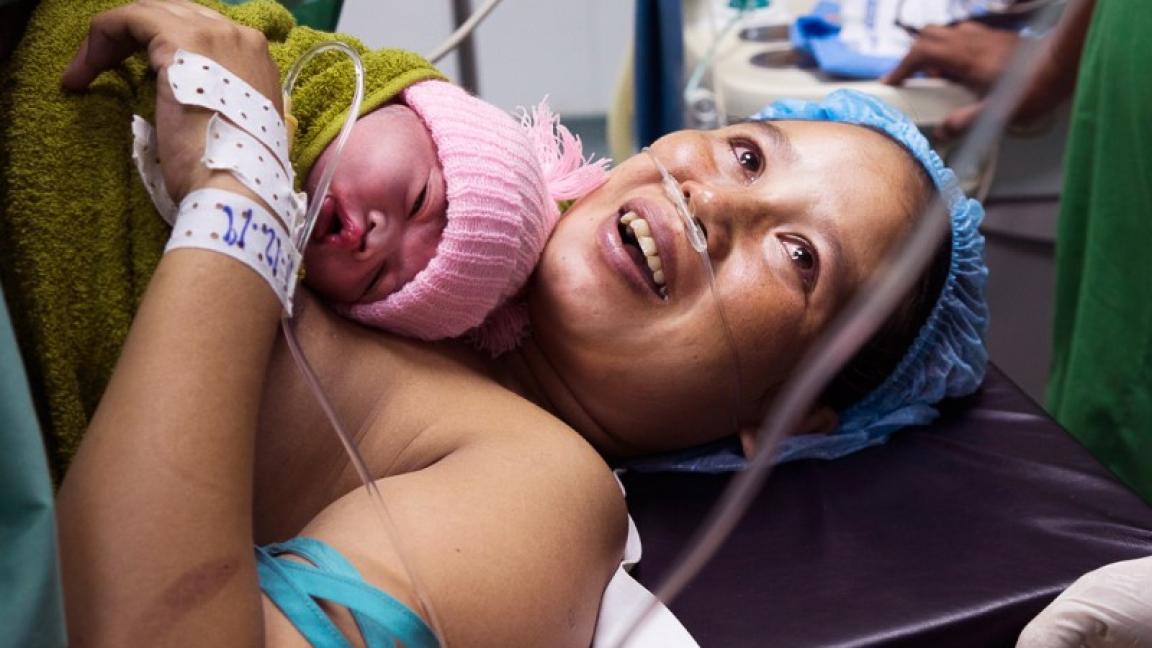 Eine Person, die mit einem Baby in einem Krankenhausbett liegt.