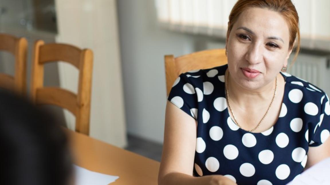 Silvia Feraru sitzt an einem Tisch und hat Papiere in der Hand.