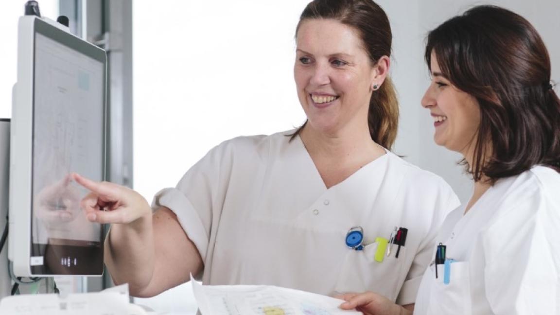 Zwei Krankenhauskräfte schauen auf einen Bildschirm.