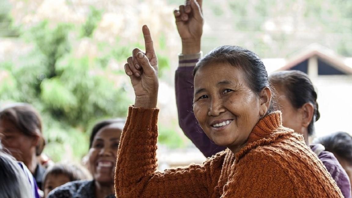 Eine Gruppe von Menschen, zwei davon heben die Hand zu einer Wortmeldung