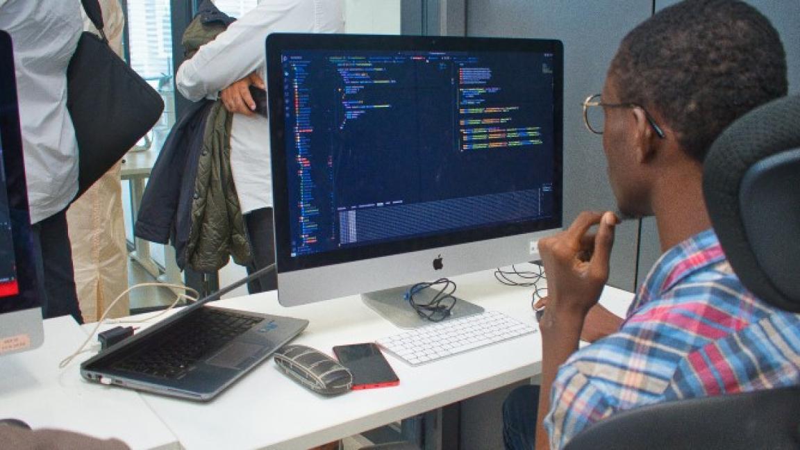 Ein junger Mann programmiert an einem Rechner in einem Schulungsraum.