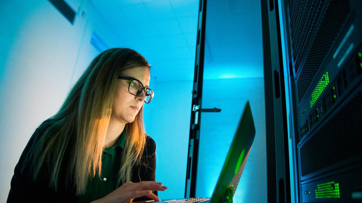 Junge Frau im Halbdunkel vor einem Laptop