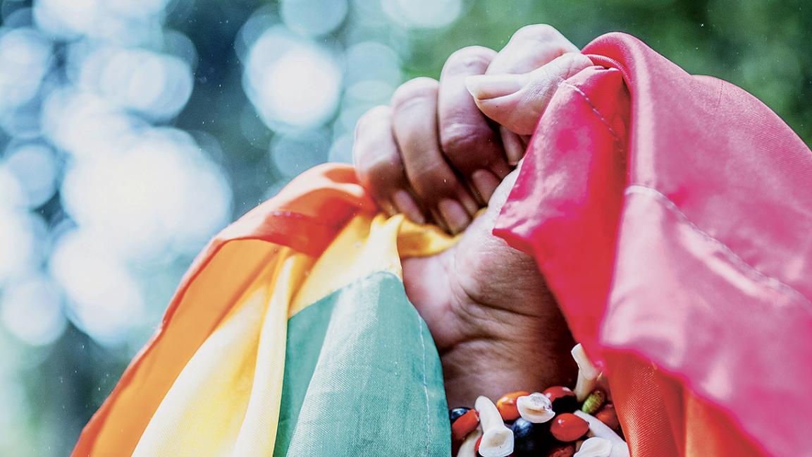 Eine geballte Faust mit der Regenbogenfahne in der Hand