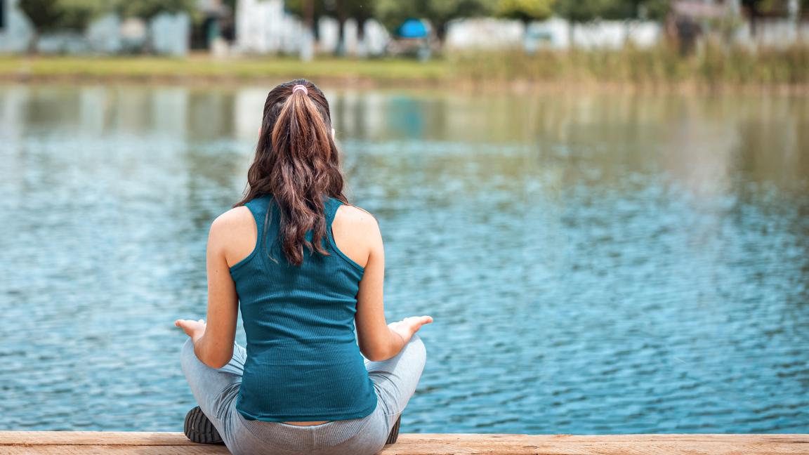 Frau im Lotussitz an einem See