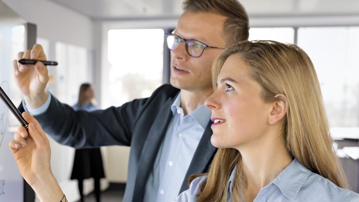 Digitalexpert:innen zeigen etwas an einem Whiteboard