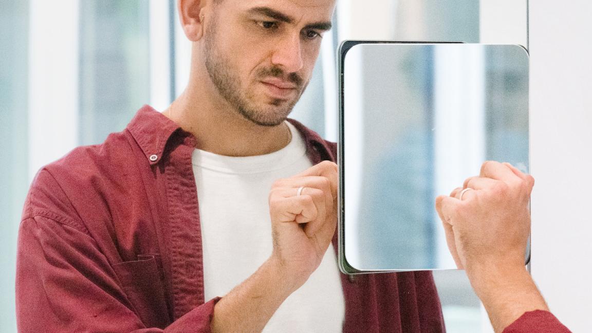 Mann interagiert mit seinem Spiegelbild vor einer Installation