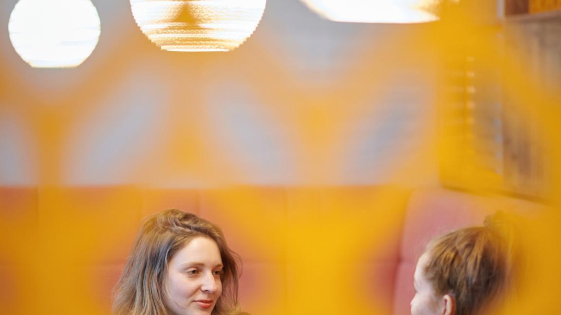 Zwei junge Frauen unterhalten sich an einem Tisch