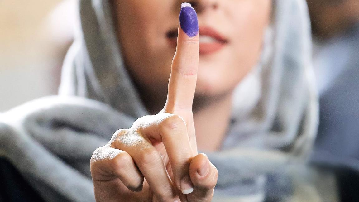 Eine junge Frau mit Kopftuch hält ihren Zeigefinger mit einer violett farbenen Fingerkuppe in die Kamera