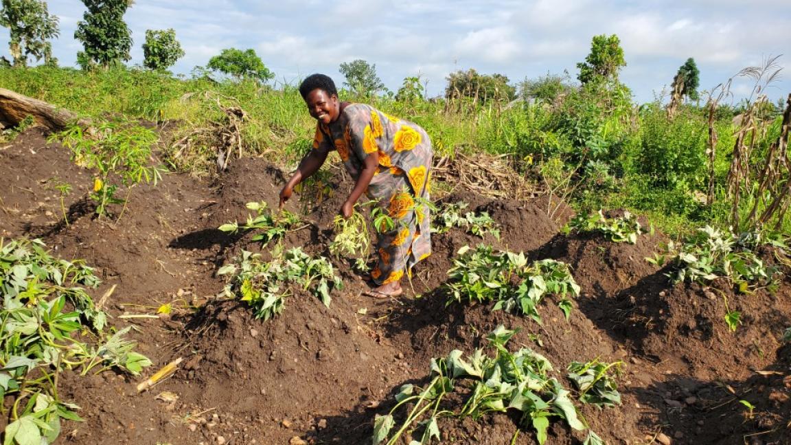 A woman stands in a field of crops and smiles.