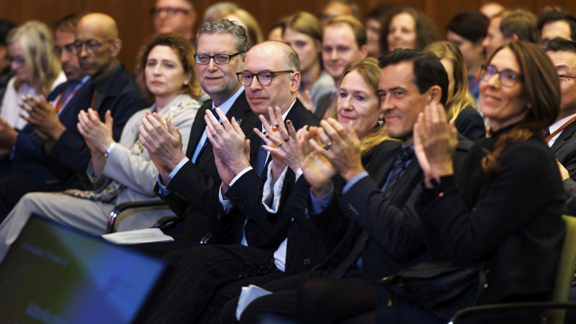 Several persons sitting in a row, clapping