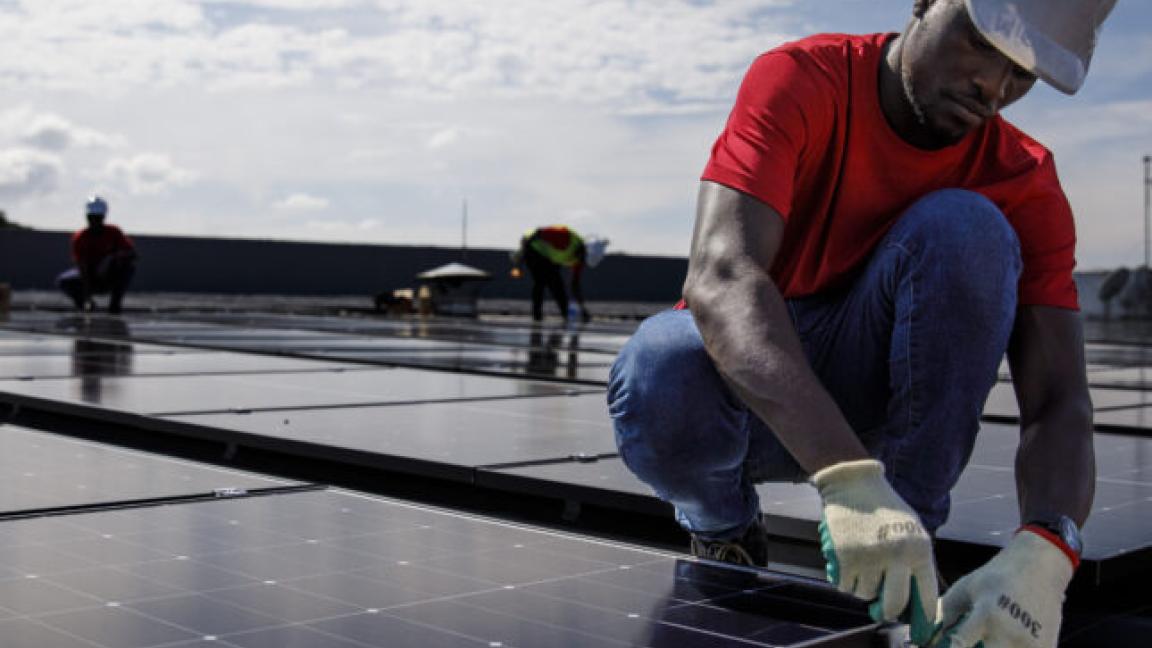 Ein Arbeiter bringt ein Solarpanel auf einem Dach an