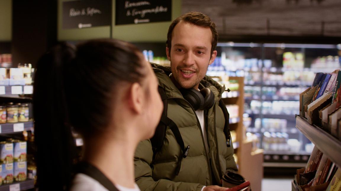 Ein Mann unterhält sich im Supermarkt mit einer Mitarbeiterin