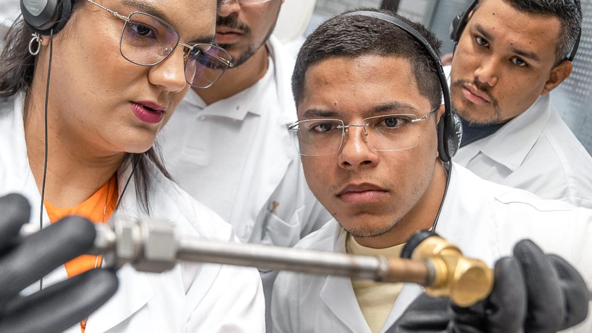 Four people look at a technical device during a training session.