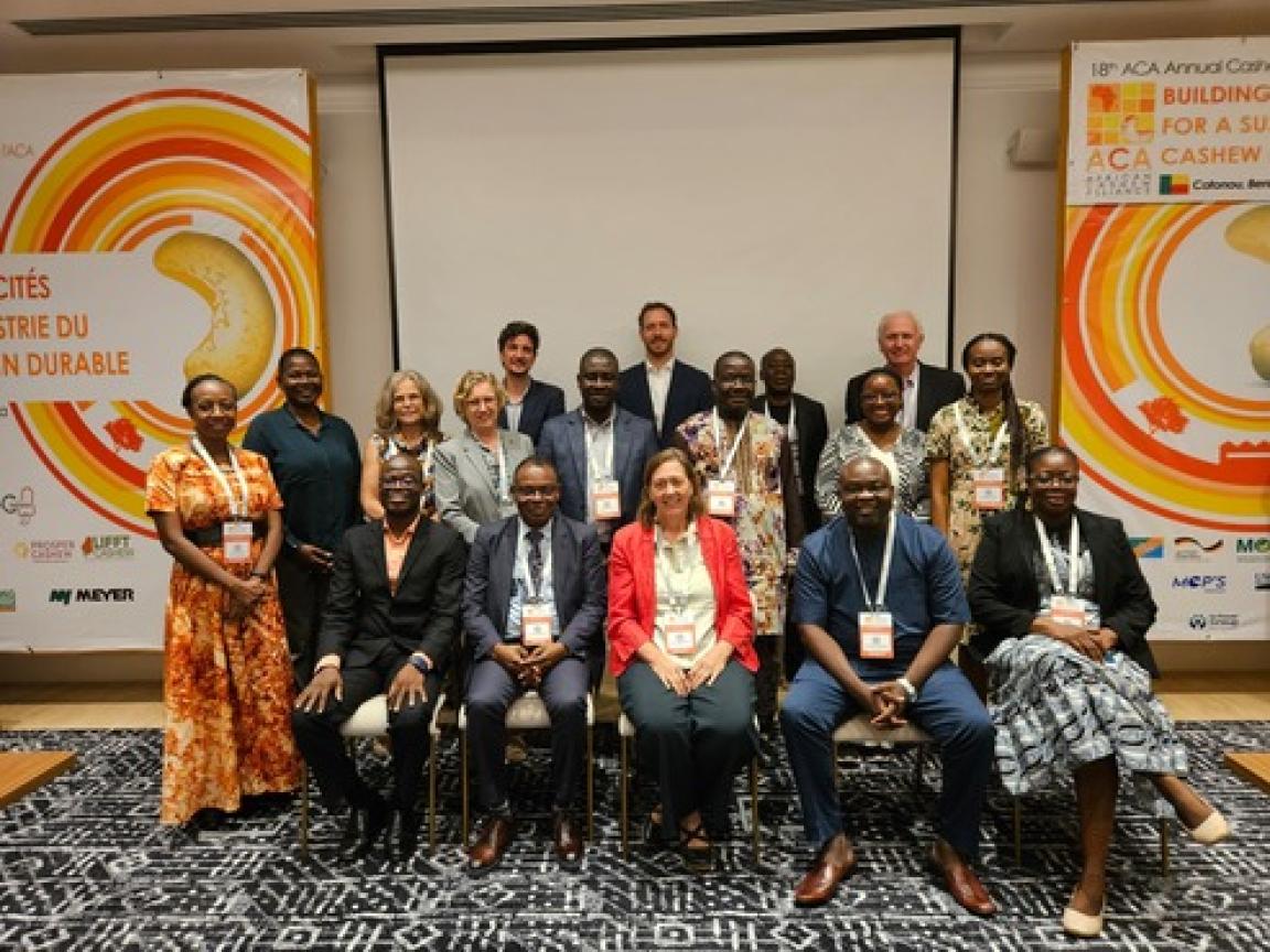 Mehrere Menschen sitzen für ein Gruppenbild eines Cashew-Projektes in einem Raum.