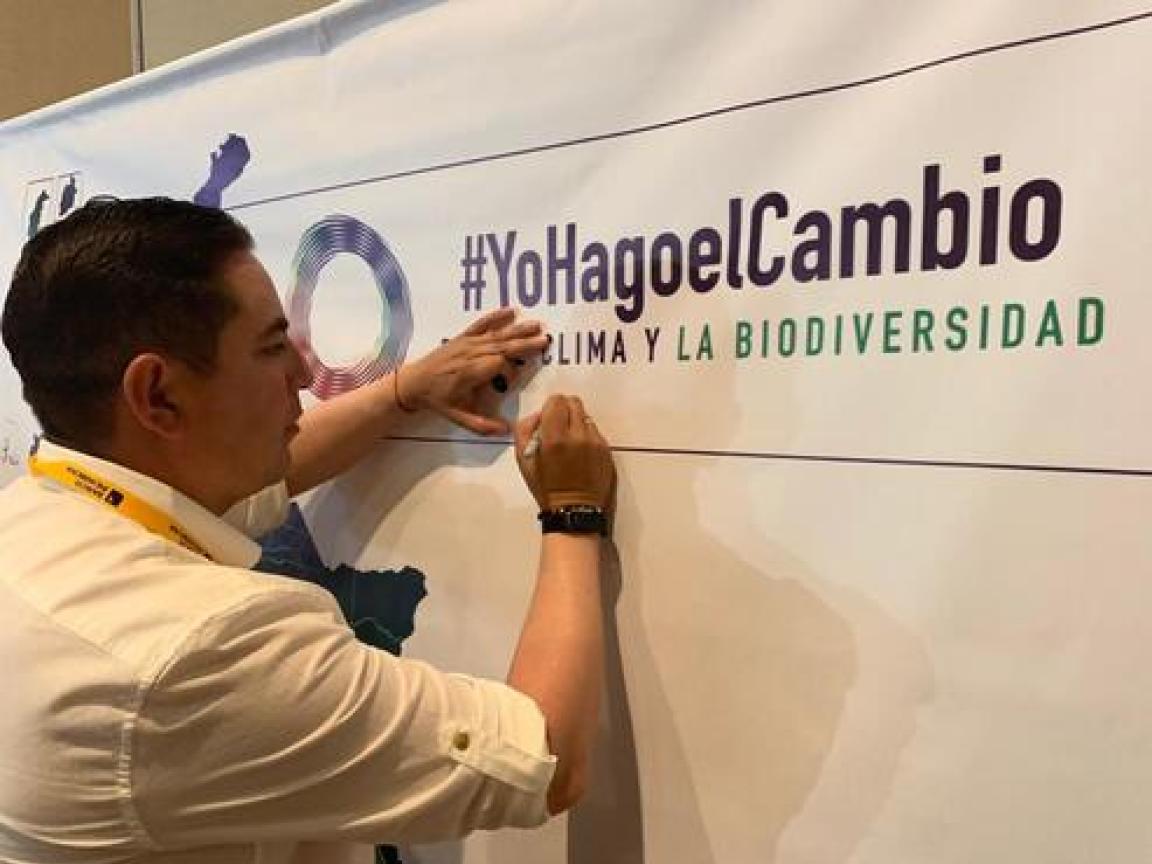 Ein Mann unterschreibt ein spanisch geschriebenes Plakat mit der Aufschrift "#YoHagoelCambio"