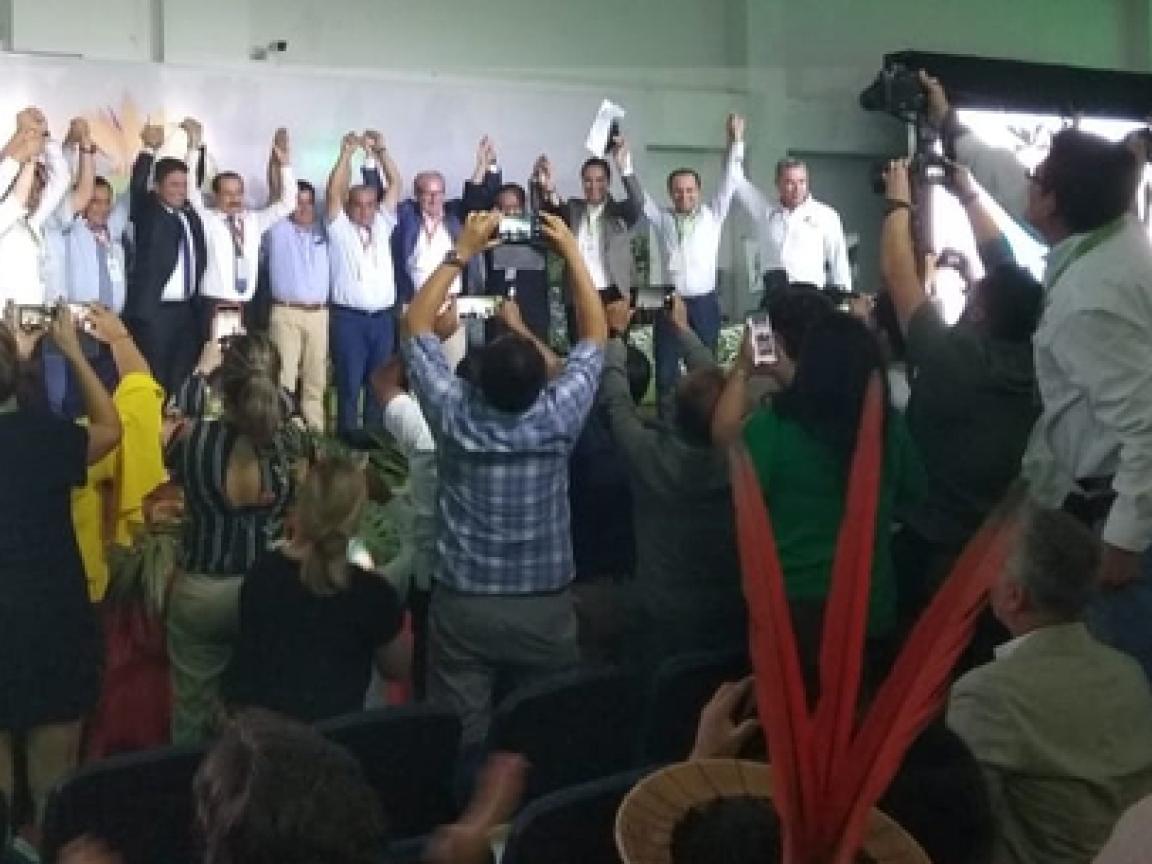 Eine Gruppe von Menschen jubelt Menschen zu, die auf einer Bühne stehen.