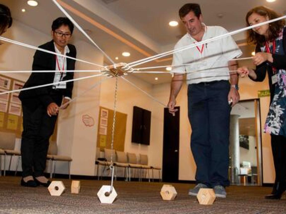 Eine Gruppe von Personen in Anzügen spielt ein kooperatives Angelspiel.