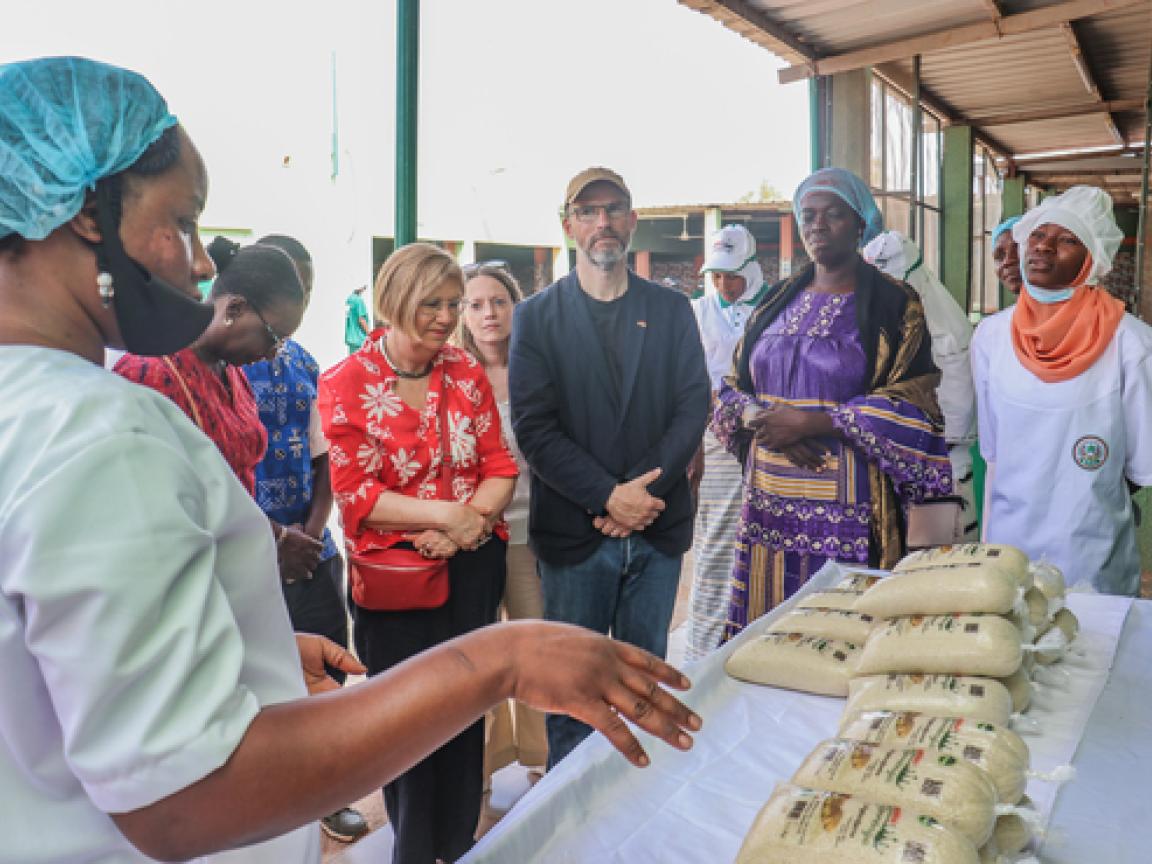 Eine Gruppe von Menschen steht um einen Tisch mit gefüllten Tüten. Links im Bild gestikuliert eine Frau.