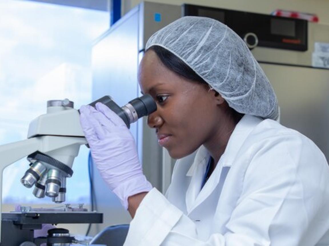 Wissenschaftlerin untersucht Proben an einem Mikroskop.