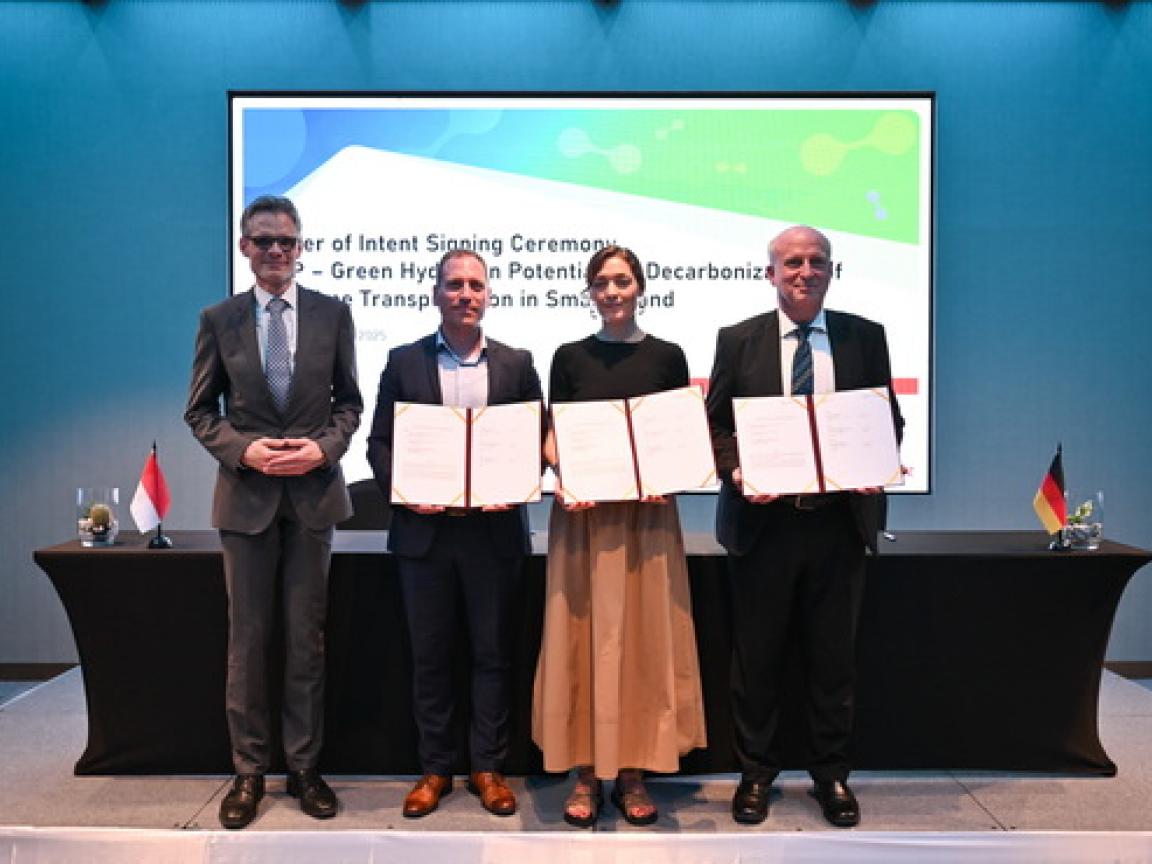 Vertreter von Neuman & Esser (NEA) Ltd., Hydrogen de France (HDF) Energy, and GIZ halten die unterzeichneten Absichtserklärungen in die Kamera.