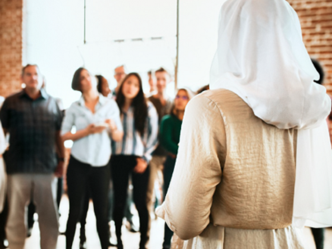 A woman standing in front of gathered people.