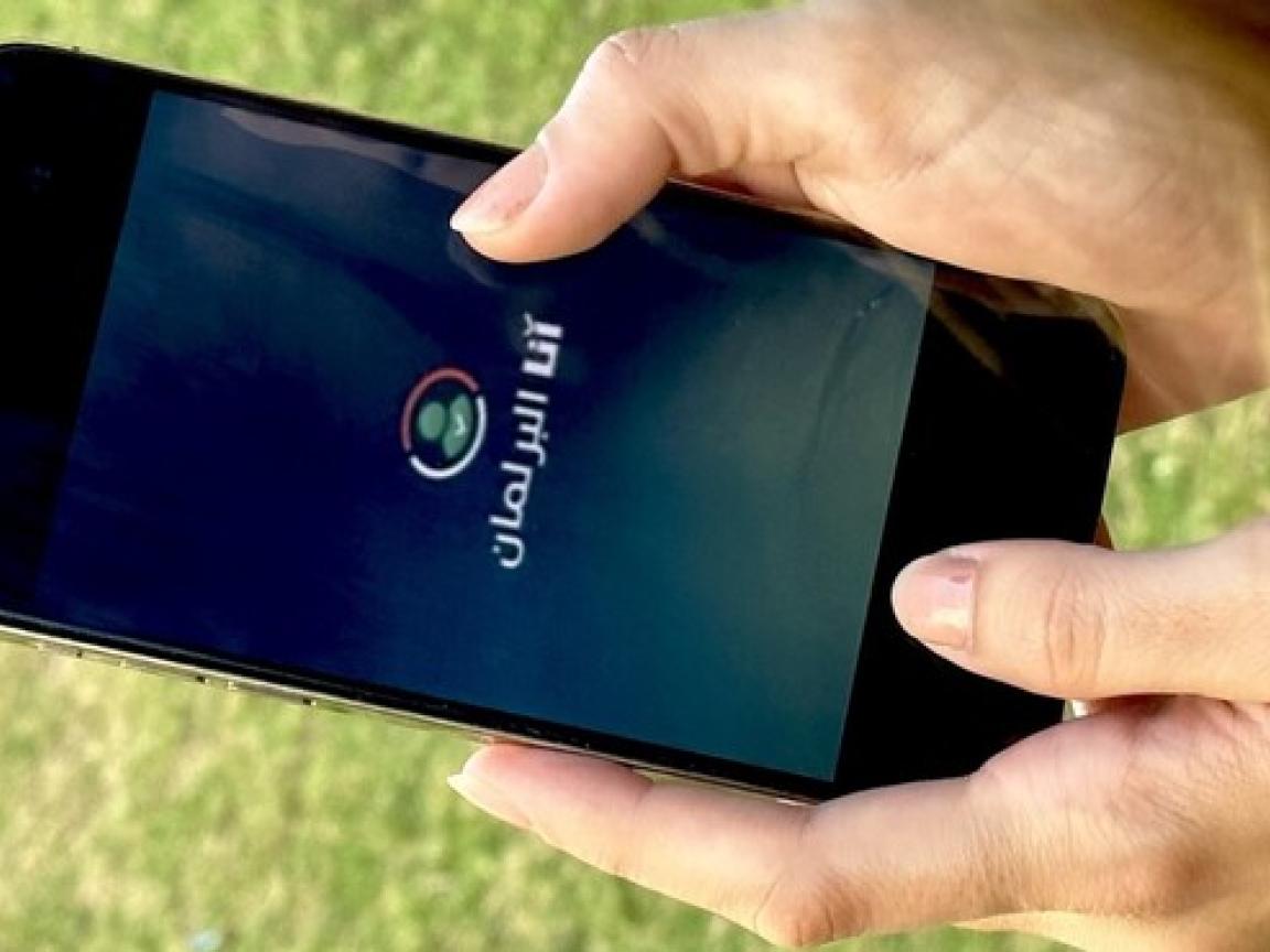 Hand holding a smartphone showing the Logo of the application "I am Parliament"