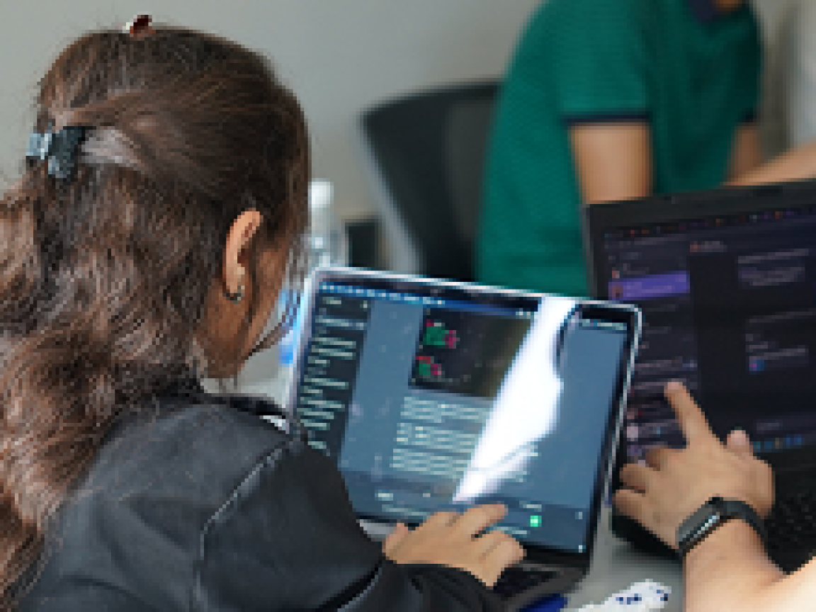 Two persons sitting at a desk working on their Laptops