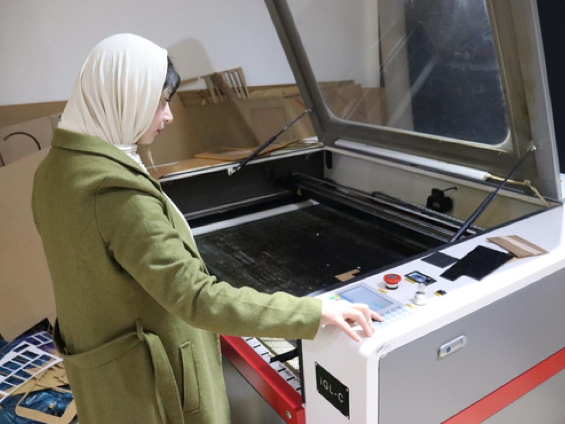 A woman operating a laser cutter