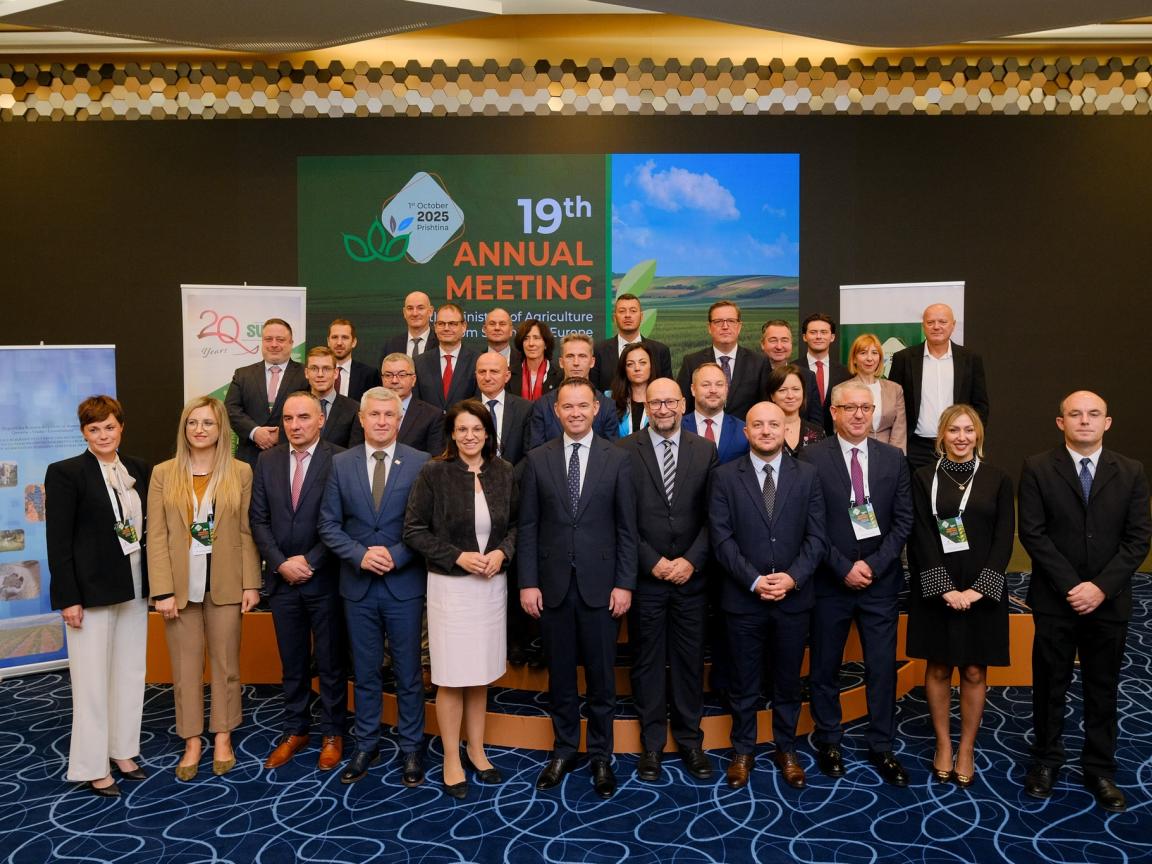 A group of people in business attire at a meeting, taking a group picture.