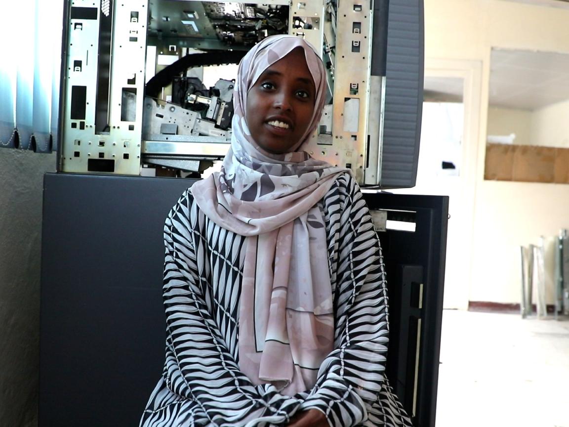A woman in hijab is sitting in front of a technical device.