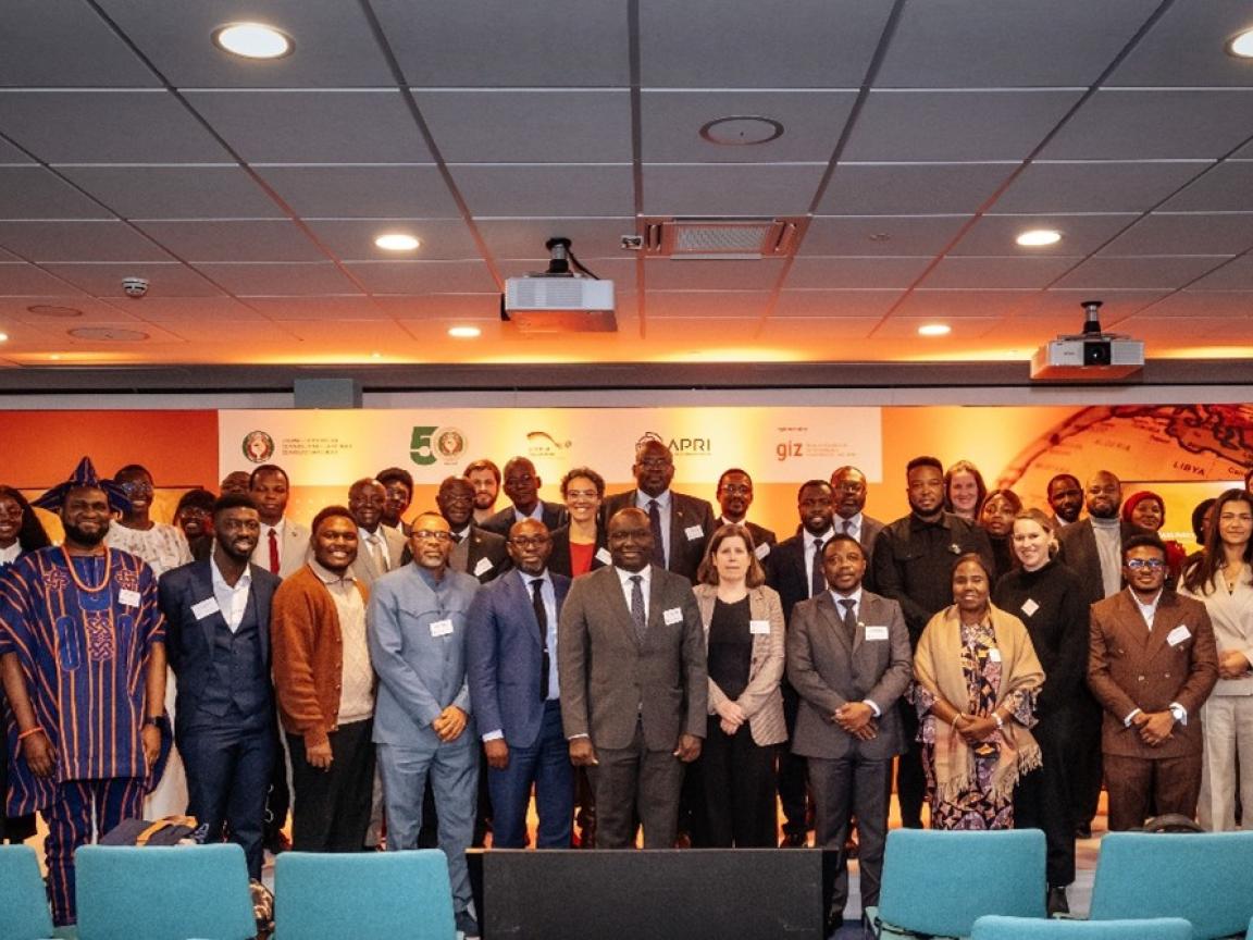 A large group of people a posing for a group picture on a stage at an event.