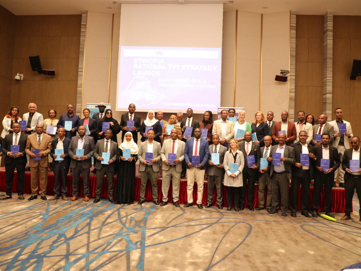 A group of people is standing in front of the stage of a conference room.
