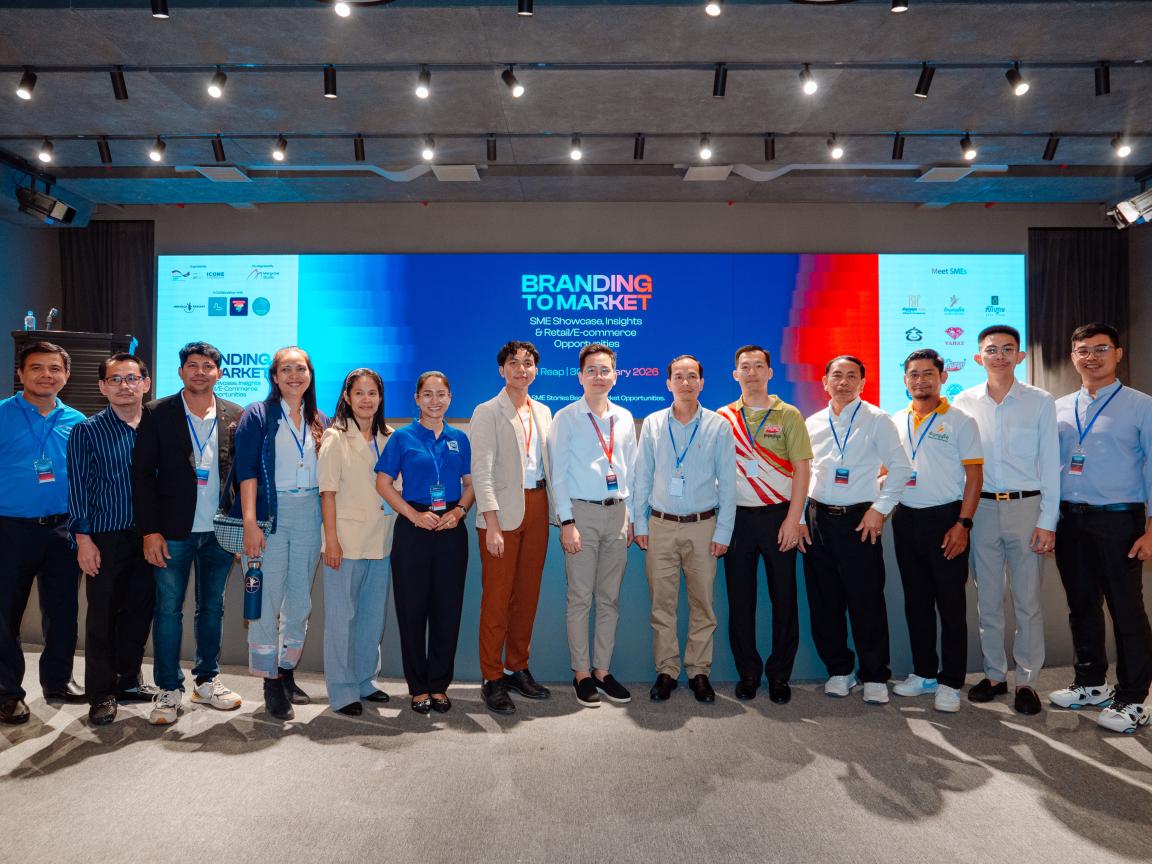 A group of people is standing next to each other in a line in front of a large screen that reads 'Branding to Markets'.