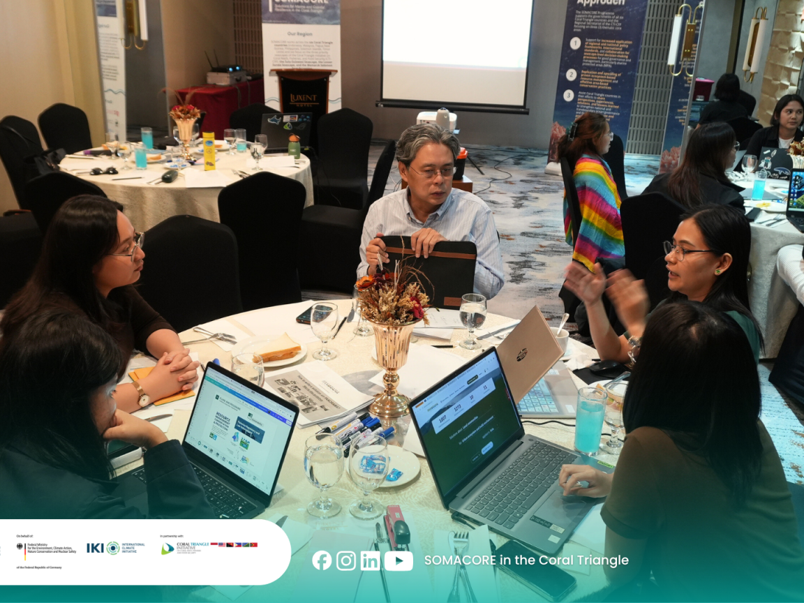 Five people are working on a table with some laptops during a workshop of the project "SOMACORE".