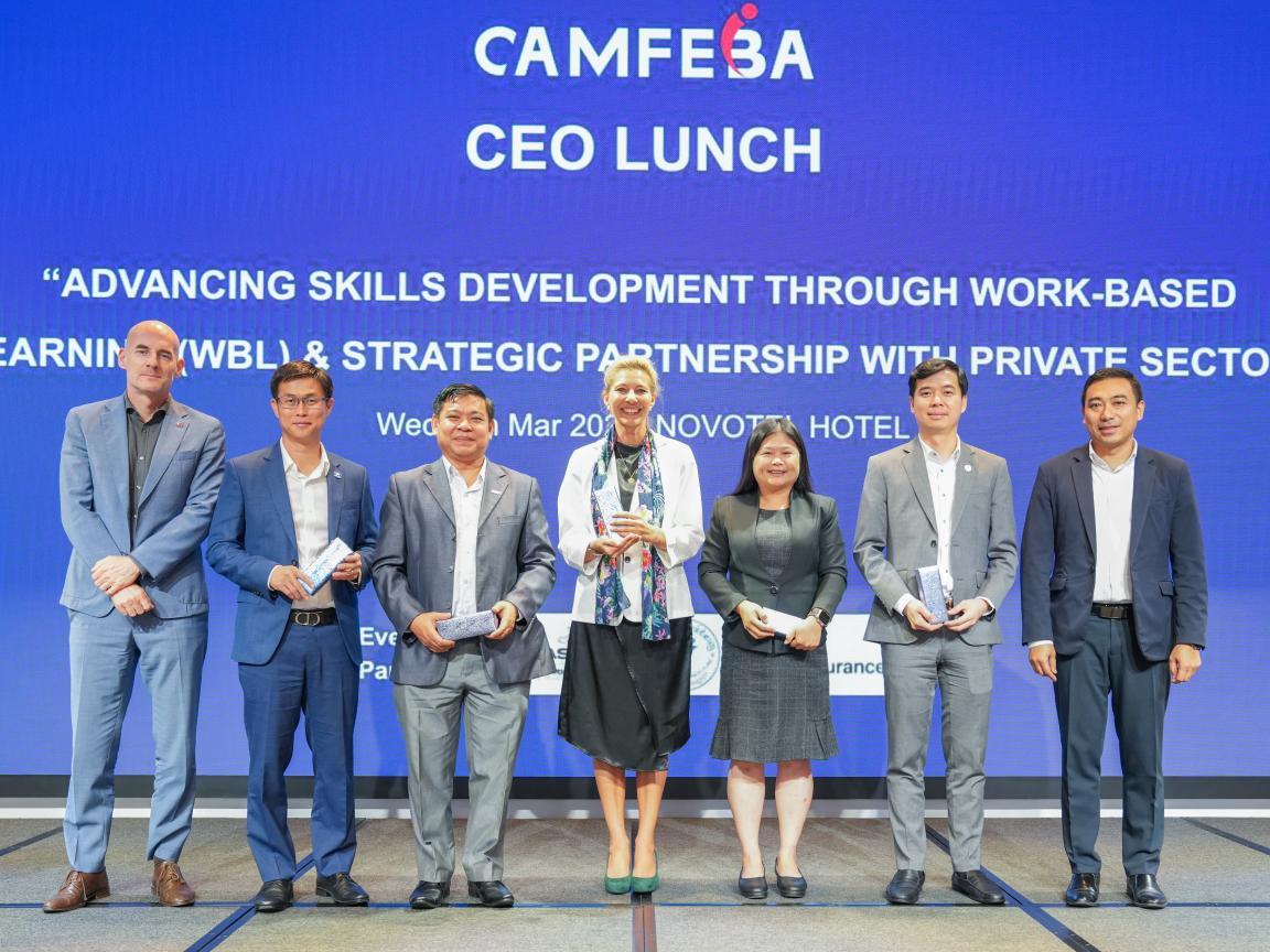 Seven people are taking a picture in front of a blue screen during a CEO Lunch meeting.