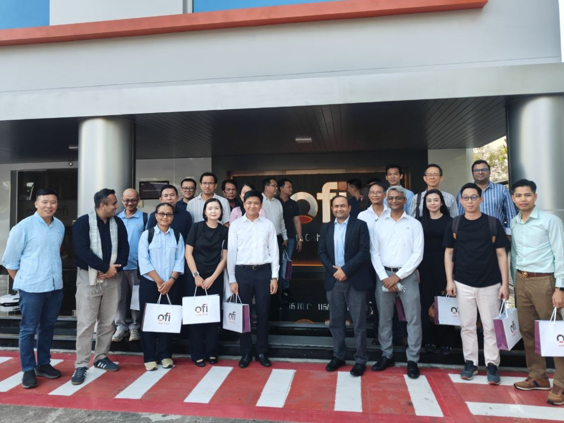 A group of people in front a building of Olam Food Ingredients (ofi), some are holding paper bags of ofi.