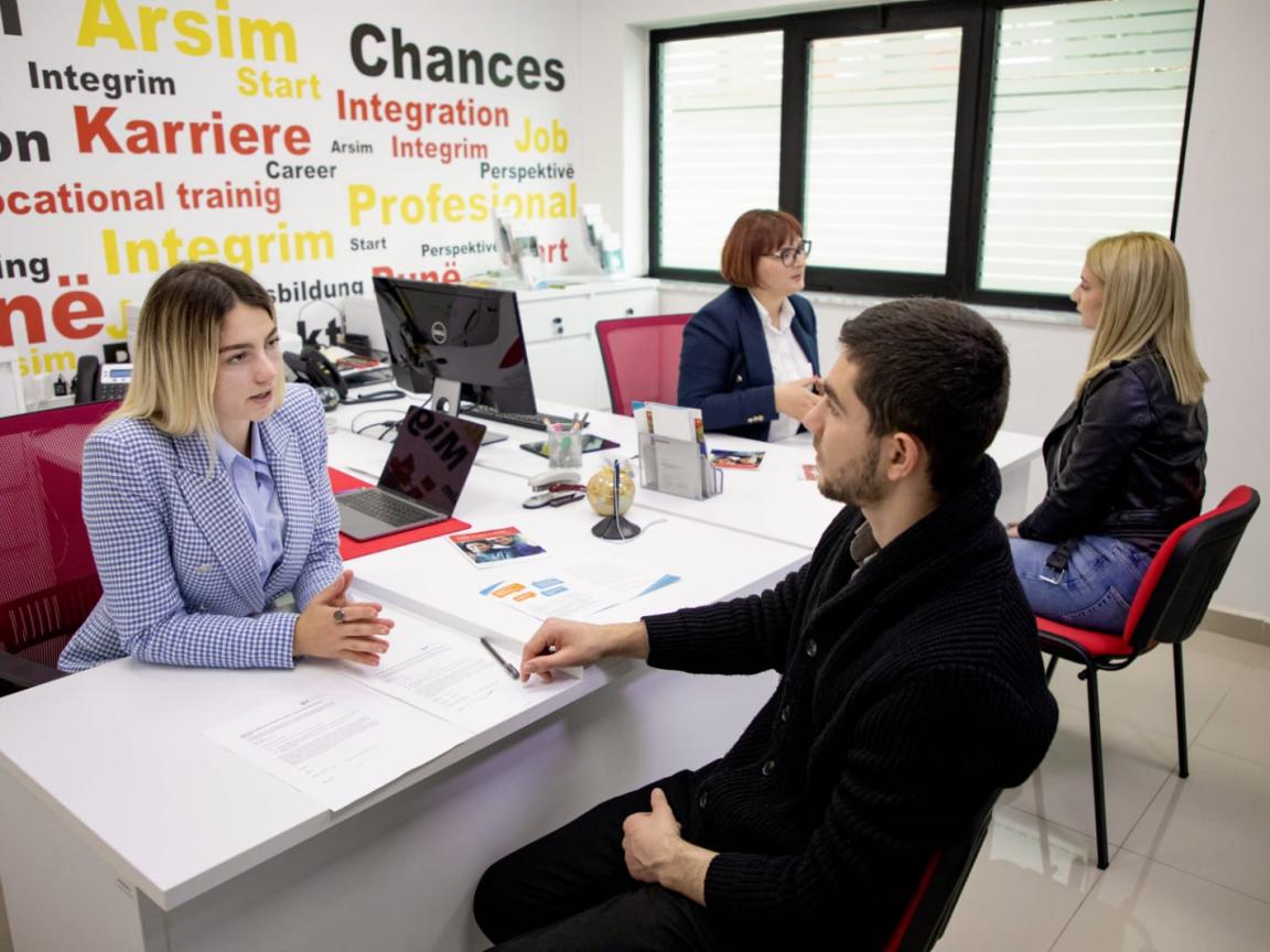 Four people having one-on-one consultations at desks in a vocational guidance and employment support office.