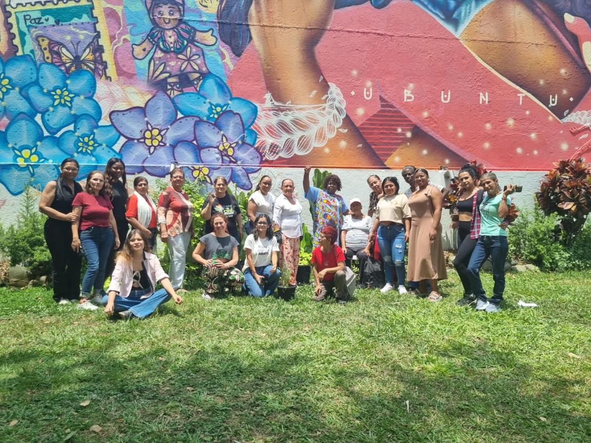 Un grupo de mujeres posan frente a un mural.