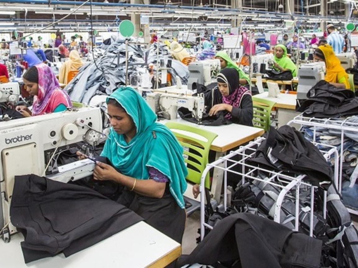 Mehrere Frauen nähen Kleidung in einer Fabrik.
