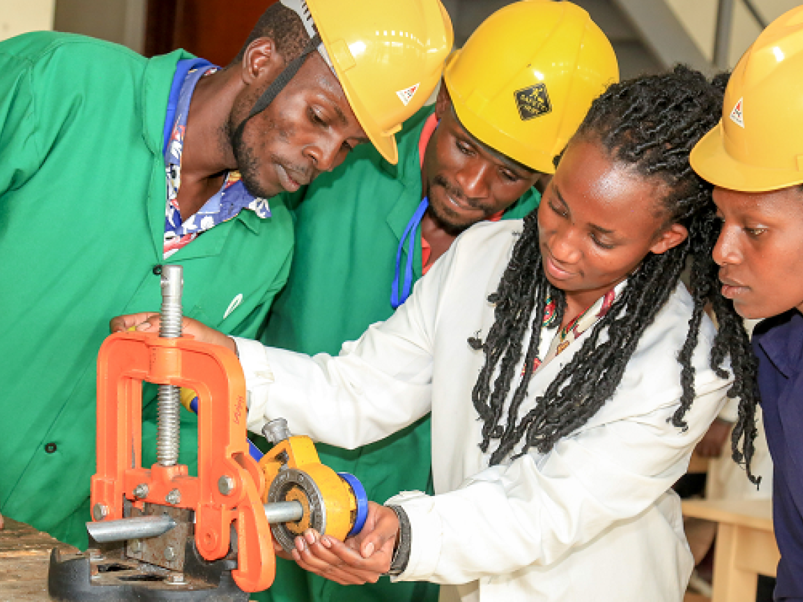 Zwei Männer und zwei Frauen aus Kenia schauen auf eine Werkbank.