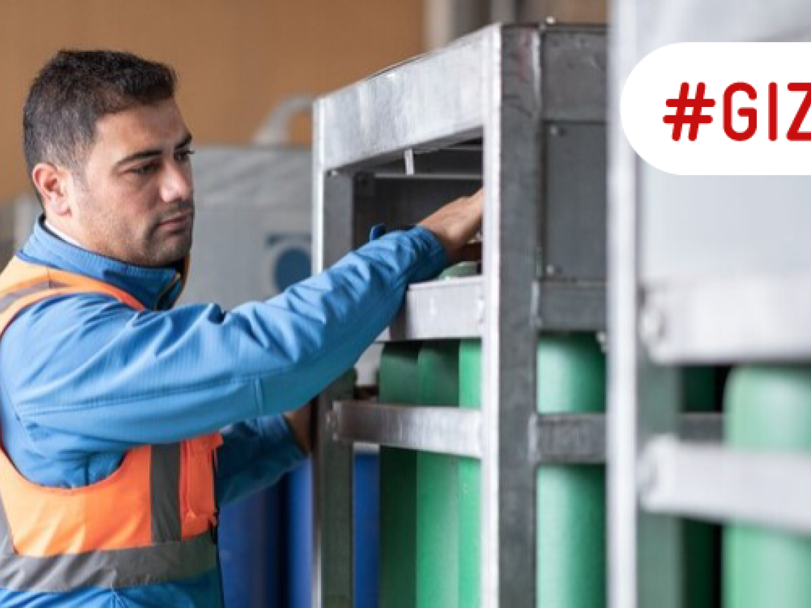A man works with hydrogen cylinders that are stored in a steel container.