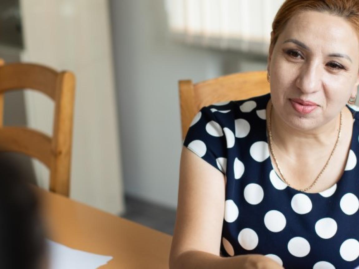 Silvia Feraru sitzt an einem Tisch und hat Papiere in der Hand.
