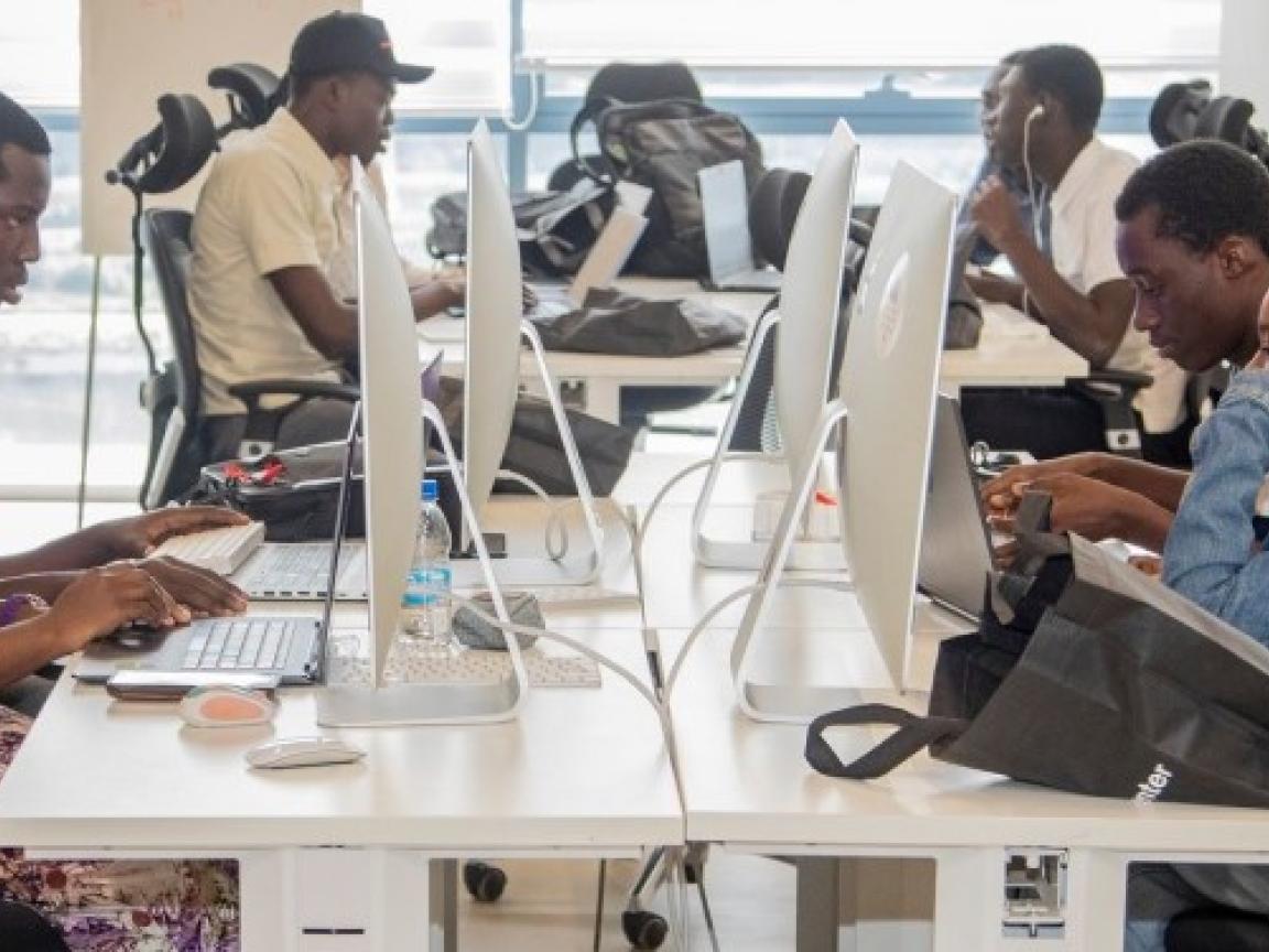 In einem Orange Digital Center sitzen sieben junge Menschen konzentriert vor Computerbildschirmen.