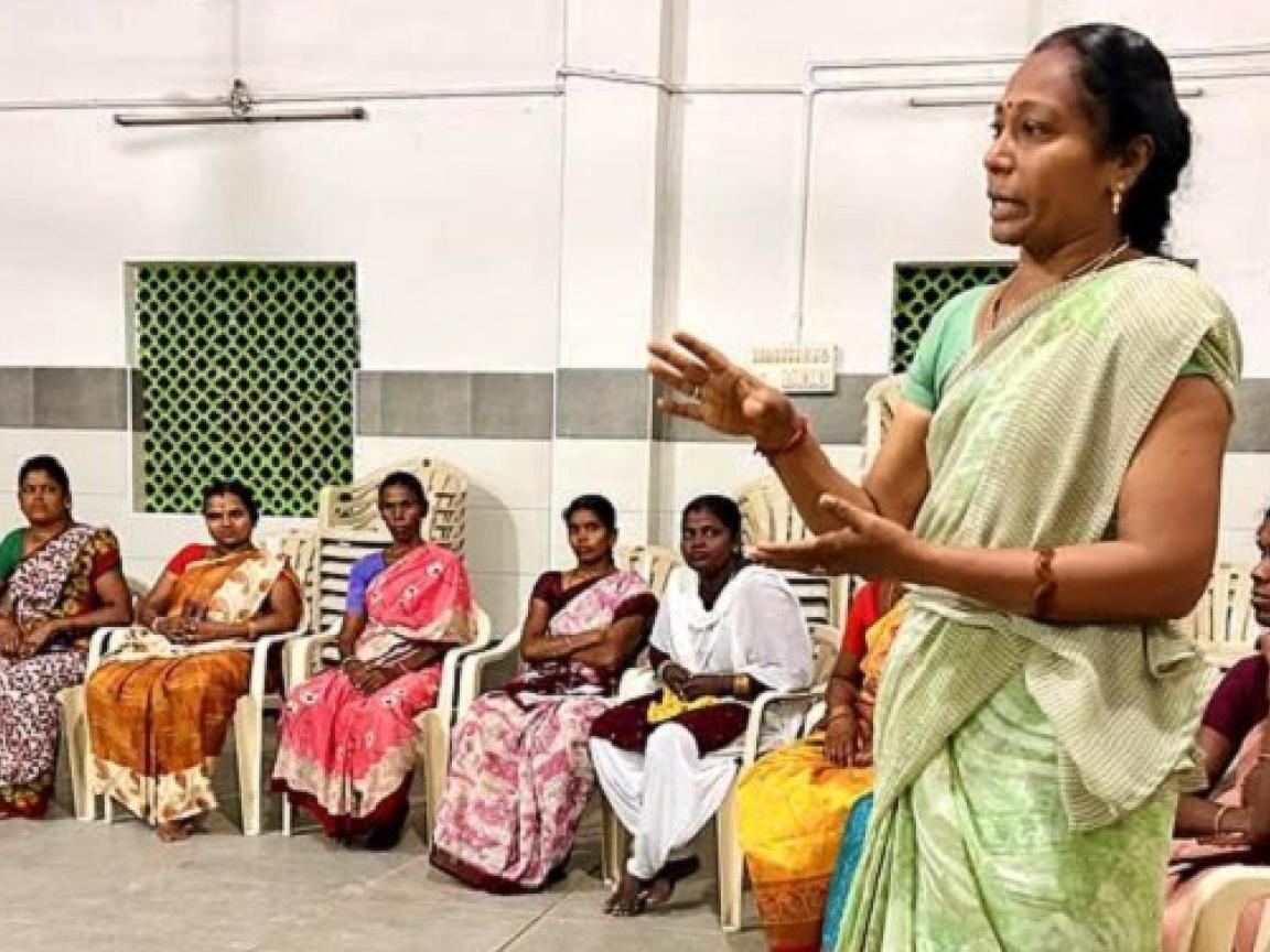 Eine Gruppe von Frauen, die bei einer art Vortrag in einer Halle im Kreis sitzen.