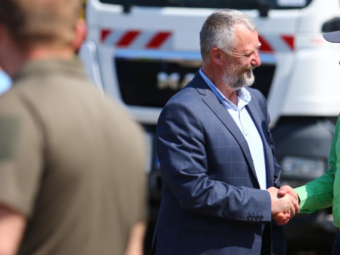 Zwei Männer stehen vor einem Müllauto und schütteln sich die Hand.